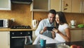 Happy young couple using digital tablet computer while sitting in the kitchen and having breakfast in the morning Royalty Free Stock Photo