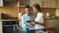 Happy young couple using digital tablet computer while sitting in the kitchen and having breakfast in the morning Royalty Free Stock Photo