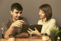 Happy young couple using digital tablet computer sitting at the table Royalty Free Stock Photo