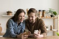 Happy young couple using Internet technologies on gadgets at home