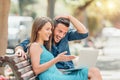 Happy young couple using laptop computer sitting on bench in city outdoor Royalty Free Stock Photo