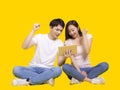 Happy young couple using tablet computer.Isolated on yellow background. Celebrating success Royalty Free Stock Photo