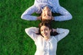 Happy young couple view from top with crossed arms under head smiling looking at camera lying on a green grass meadow with sunset Royalty Free Stock Photo