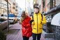 Happy young couple walking city street, looking at each other with smile, wearning in bright yellow and red down jackets Royalty Free Stock Photo