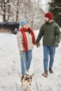 Happy young couple walking cute corgi dog in winter forest Royalty Free Stock Photo