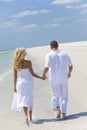 Happy Young Couple Walking Holding Hands on Beach Royalty Free Stock Photo