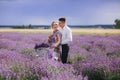 Happy young couple are walking with retro bicycle in lavender field. man is hugging her woman in purple dress and with hairstyle Royalty Free Stock Photo