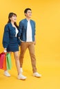 Happy young couple walking with shopping bags and looking at each other  on yellow Royalty Free Stock Photo