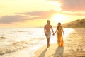 Happy young couple walkingon beach at sunset
