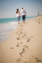 Happy young couple walking on a tropical beach. Lovers in full body length on beach. Back rear view. Royalty Free Stock Photo