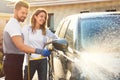 Happy young couple washing car at backyard