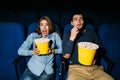 Happy young couple watching comedy movie in cinema, smiling