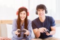 Happy young couple wear headphone and holding joystick playing video game Royalty Free Stock Photo