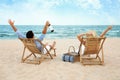 Happy young couple with wine  on deck chairs at  beach Royalty Free Stock Photo