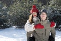 Happy young couple in winter in forest. Guy rolls the girl on his back Royalty Free Stock Photo