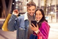 Happy young couple with Xmas shopping bags using cellphone outdoor Royalty Free Stock Photo