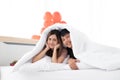 A happy young couples are in bed under the blanket. Royalty Free Stock Photo