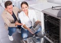 Happy young customers choosing new dish washing machine Royalty Free Stock Photo