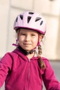 Happy young cyclist portrait, little school age child in a bicycle helmet, vertical shot, face closeup. Young caucasian girl