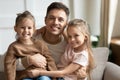 Happy young dad embracing cute kids daughters looking at camera Royalty Free Stock Photo