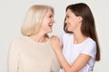Happy young daughter embracing mature mother laughing isolated on background