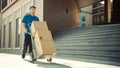 Happy Young Delivery Man Pushes Hand Truck Trolley Full of Cardboard Boxes and Packages For Delive Royalty Free Stock Photo