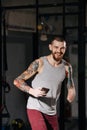 Happy young disabled armless man in a training room with a phone in hand