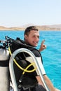 Happy young diver in a suit for diving is preparing to dive