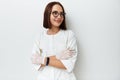 Happy young doctor intern looking away while posing against white background with crossed arms