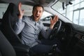 Happy young driver behind the wheel inside new car. Lifestyle scene in the car dealership Royalty Free Stock Photo