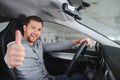 Happy young driver behind the wheel inside new car. Lifestyle scene in the car dealership Royalty Free Stock Photo