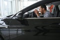 Happy young driver behind the wheel inside new car. Lifestyle scene in the car dealership Royalty Free Stock Photo