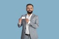 Happy young entrepreneur showing empty business card on blue studio background, mockup for design Royalty Free Stock Photo