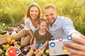 Happy young european family with little daughter on picnic taking selfie for social networks outdoor