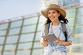 Happy young european lady tourist in hat with backpack, use tablet, enjoy travel on airport station Royalty Free Stock Photo