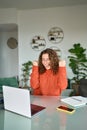 Happy young woman looking at laptop winning online, vertical.