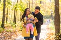 Happy young family in the autumn park outdoors on a sunny day. Mother, father and their little baby girl are walking in Royalty Free Stock Photo