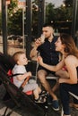 Happy young family with baby son eating lunch together at restaurant and having fun. Soft focus blurred and noise effect Royalty Free Stock Photo