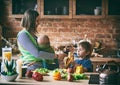 Happy young family, beautiful mother with two children, adorable preschool boy and baby in sling cooking together in a sunny kitch Royalty Free Stock Photo