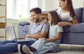 Happy young family with child sitting at home using laptop enjoying weekend. Royalty Free Stock Photo