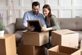 Happy young family couple unpacking belongings, looking at family photo.