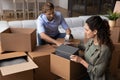 Happy young family couple unpacking carton boxes.