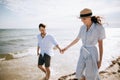 Happy young family couple walking on the beach holding hands. The concept of honeymoon and summer vacation Royalty Free Stock Photo