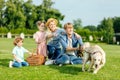 happy young family with dog resting on green grass