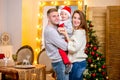 Happy young family, father, mother and son, in Christmas evening in home. They hugs and smile. New Year`s and Christmas theme.