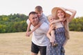 Happy young family. A father, a pregnant mother, and two little sons on their backs. Beveled wheat field on the background. Sunset Royalty Free Stock Photo