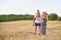 Happy young family. A father, a pregnant mother, and two little sons on their backs. Beveled wheat field on the background. Sunset Royalty Free Stock Photo