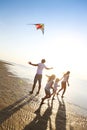 Happy young family with flying a kite on the beach Royalty Free Stock Photo