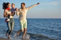 Happy young family have fun on beach run and jump at sunset Royalty Free Stock Photo