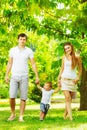 Happy young family is having fun in the green summer park outdoors on a sunny day. Mother, father and their little baby-boy are w Royalty Free Stock Photo